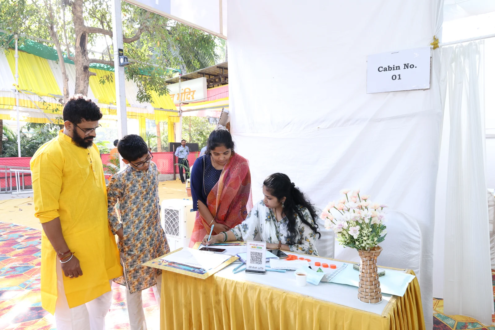 Adults and a child speaking with a doctor at a table in the medical camp