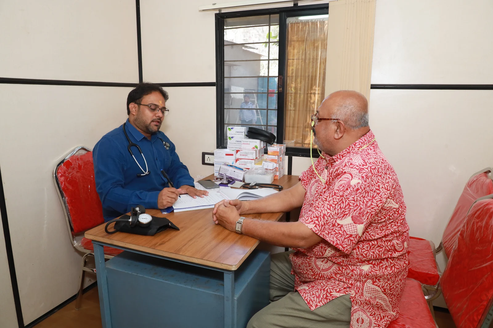 A doctor examining a seated man's wrist during the February 2025 medical camp
