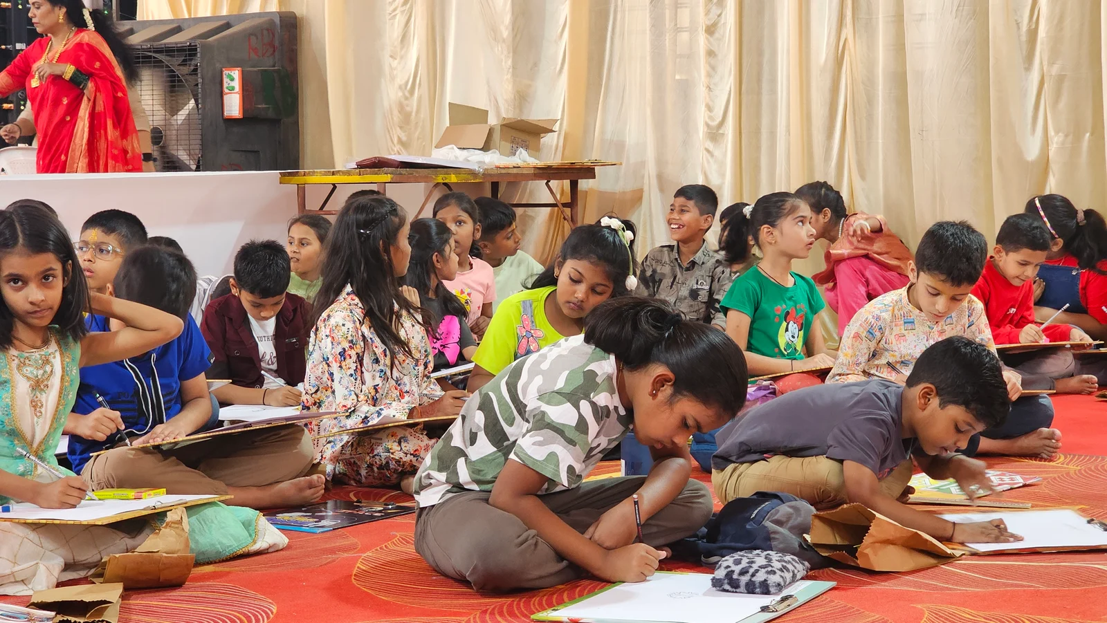 Children seated on a red carpet, drawing on boards together during the February 2026 activity