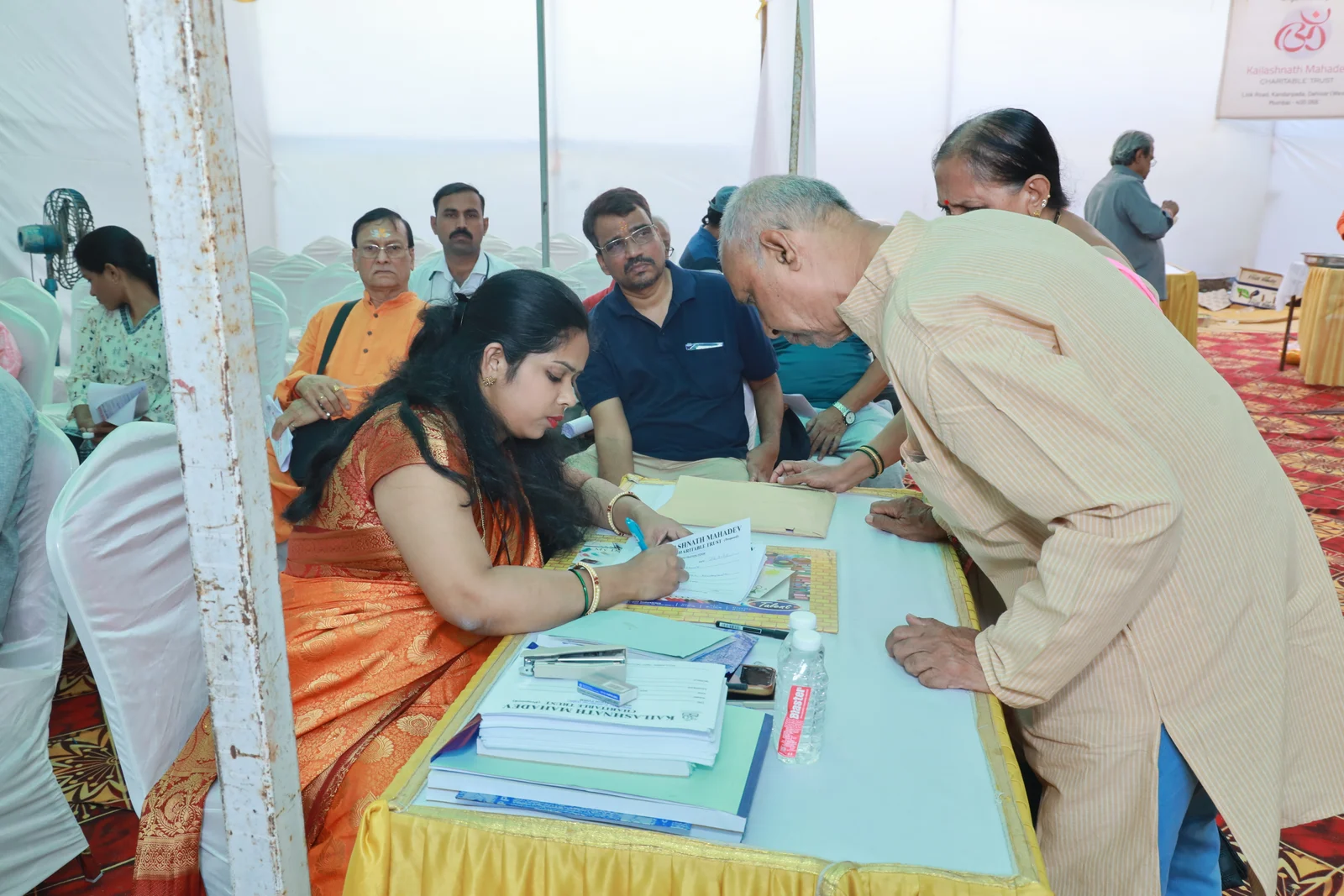 A woman at the medical camp registration table with volunteers and visitors