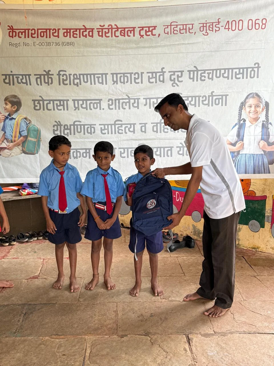 Children with their school bags beside a Trust member during the 14 July 2025 distribution