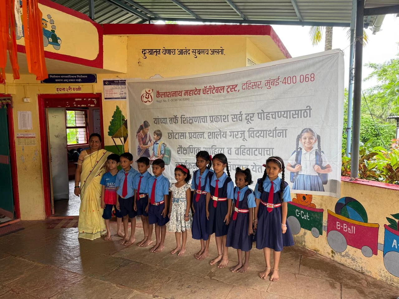 Schoolchildren in blue uniforms gathered with a Trust member in front of a school banner