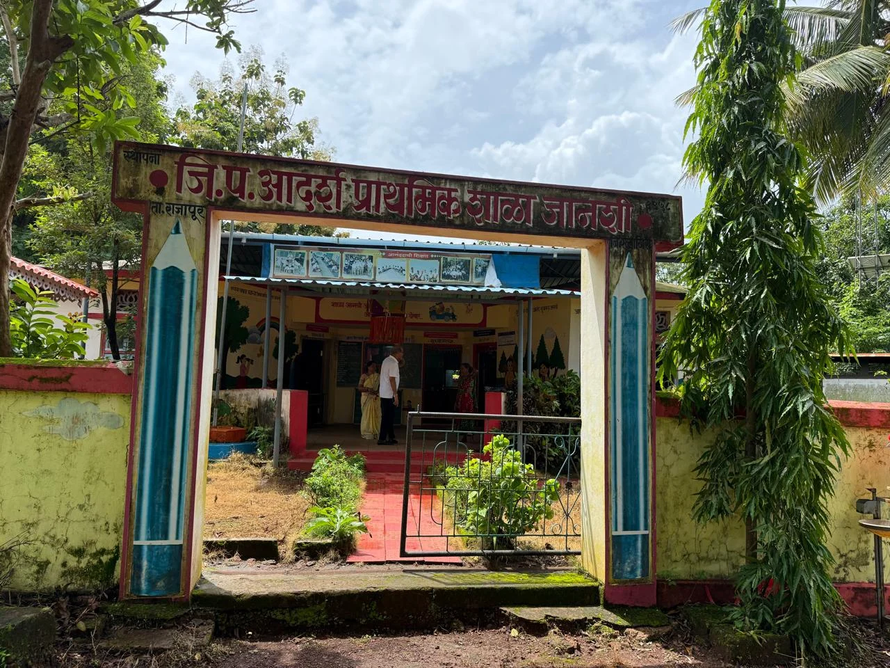 A village school entrance surrounded by trees and greenery
