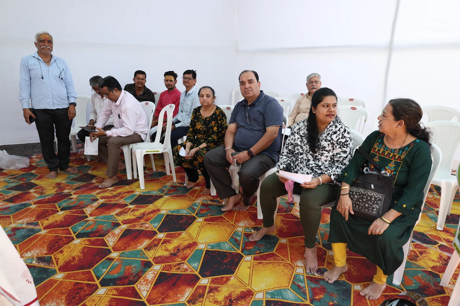 Visitors seated together on white chairs inside the March 2024 medical camp